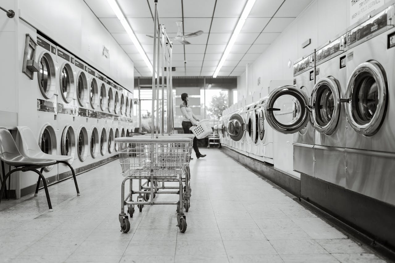 Mastering the First Impression: Your intriguing post title goes here Black and white image of a laundromat with laundry machines and a person in the background.
