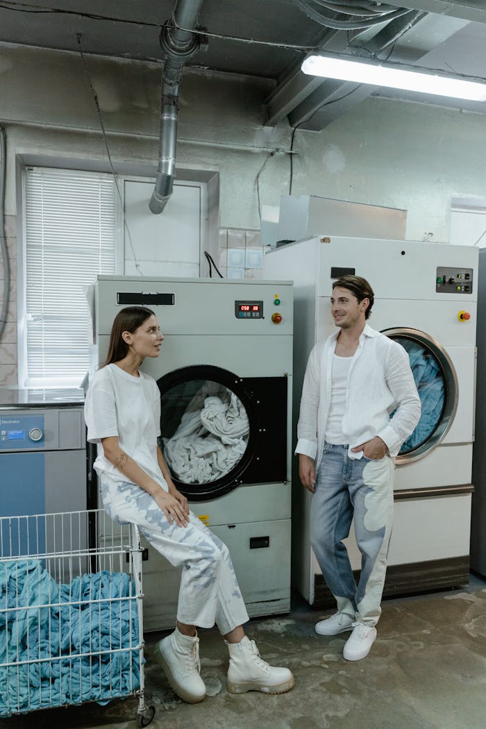 The Art of Drawing Readers In: Your attractive post title goes here Two people in white clothing converse beside industrial laundry machines in a facility.